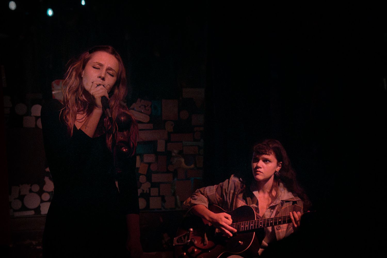 Musicians perform in a dimly lit venue with acoustic instruments.
