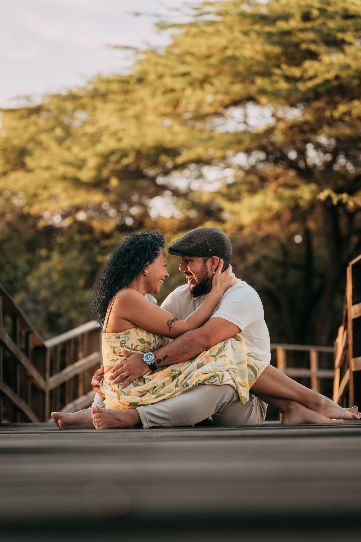 Couple sitting close together on wooden deck surrounded by trees.