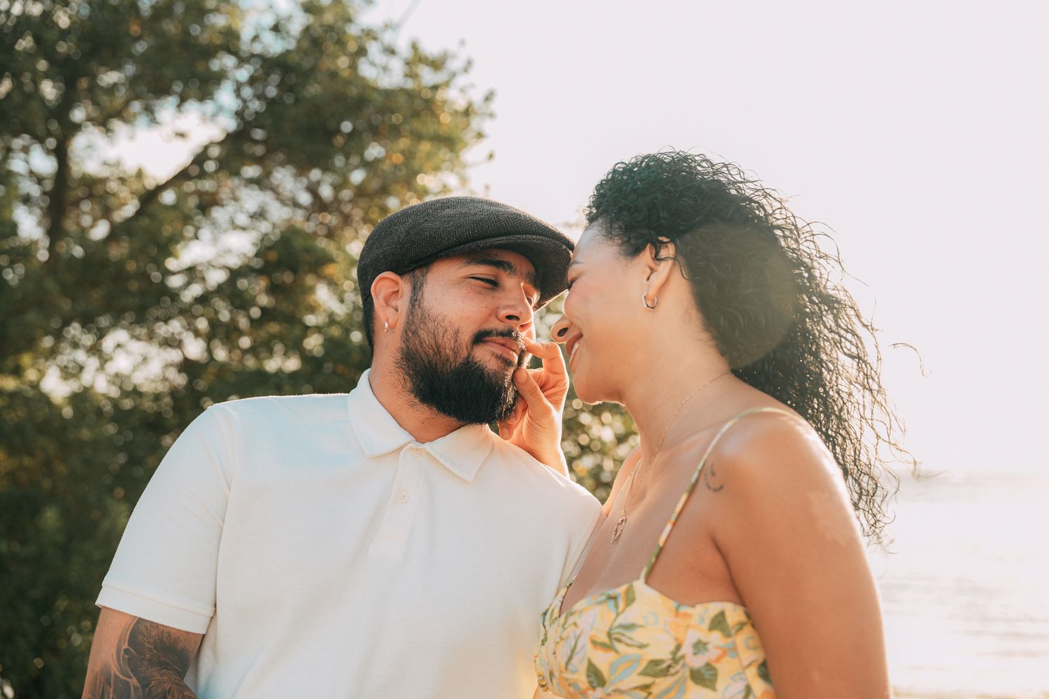 A couple shares a tender moment outdoors during golden hour.