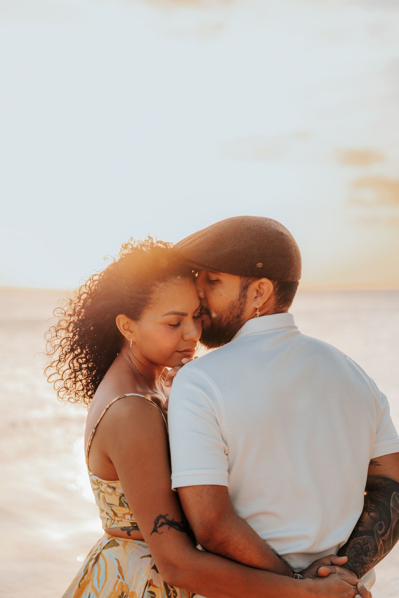Tender moment between couple during beach sunset photoshoot.