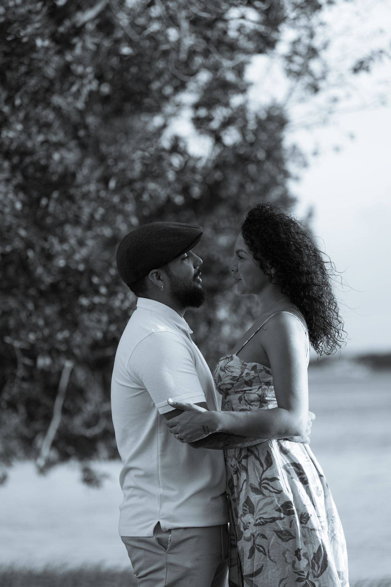 Black and white portrait of couple sharing intimate moment among trees.