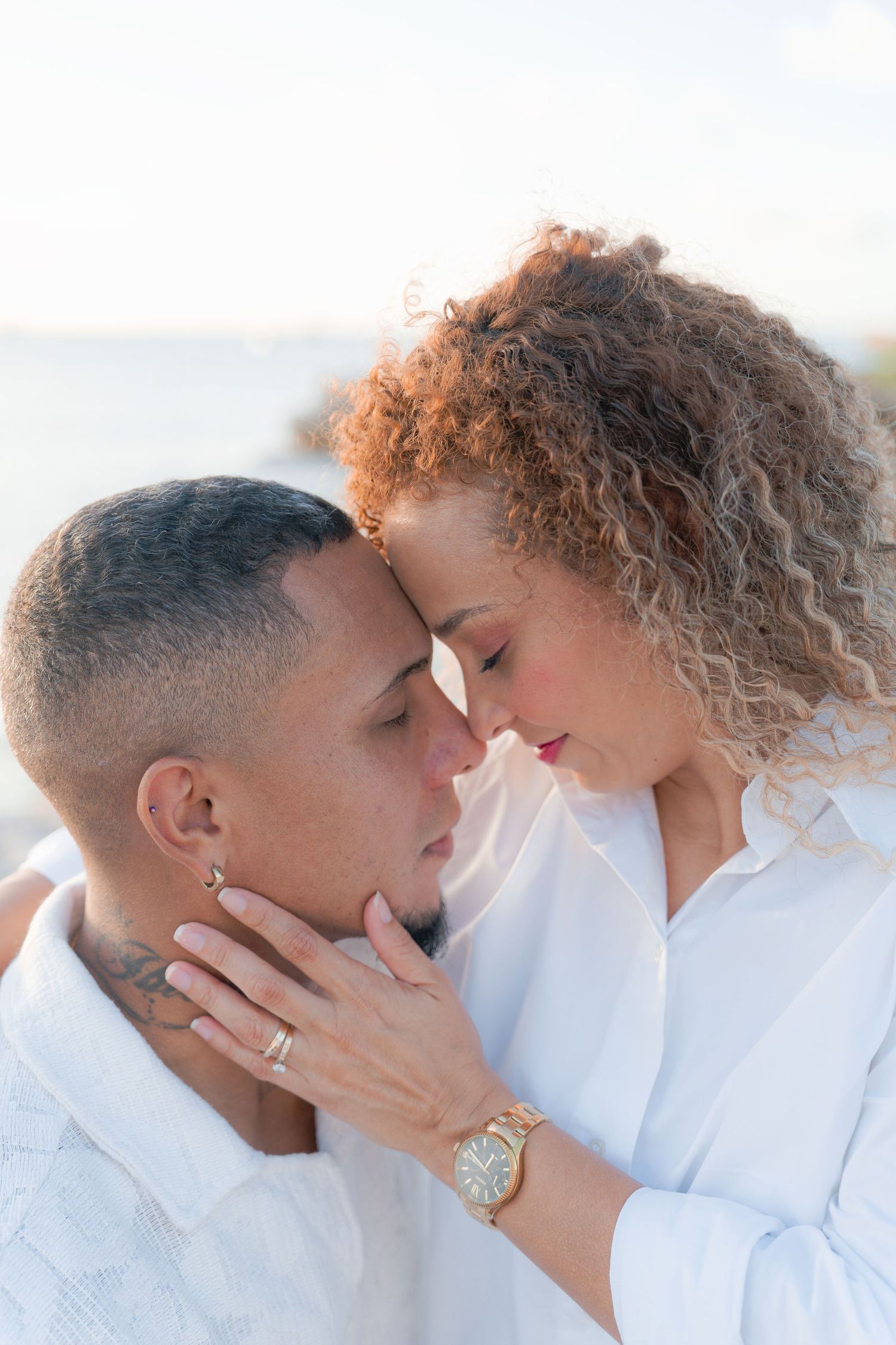 Intimate close-up of couple touching foreheads in soft natural light.
