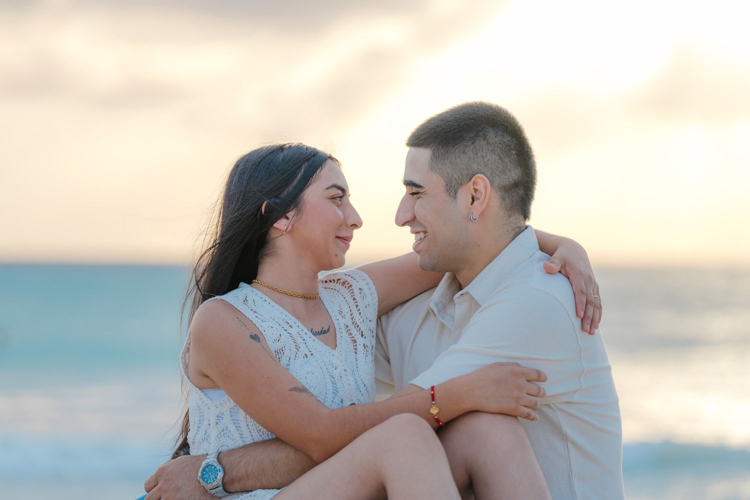 A couple embraces on the beach at sunset in a romantic series of photos.
