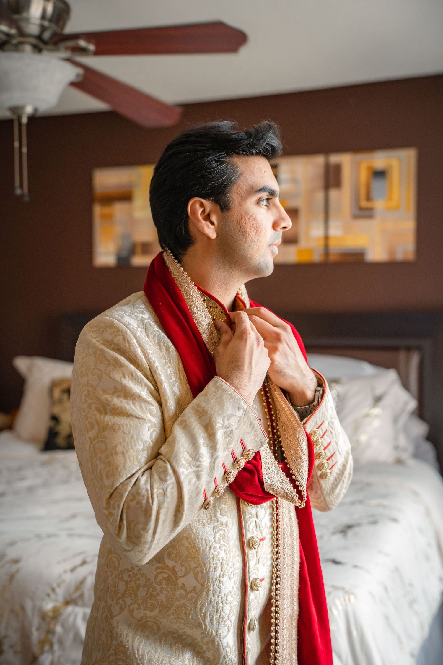 Man in traditional wedding clothing standing beside a window