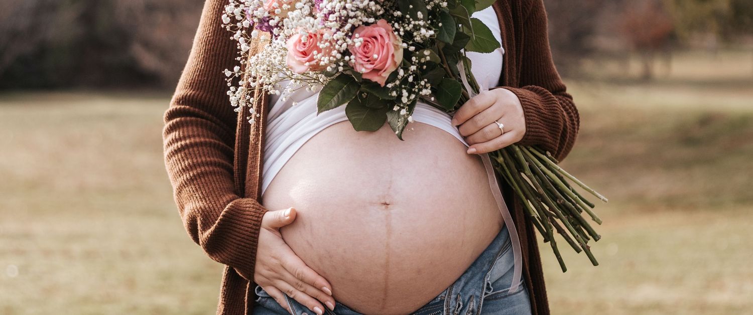 Close-up of maternity photos with floral bouquet against natural outdoor backdrop.
