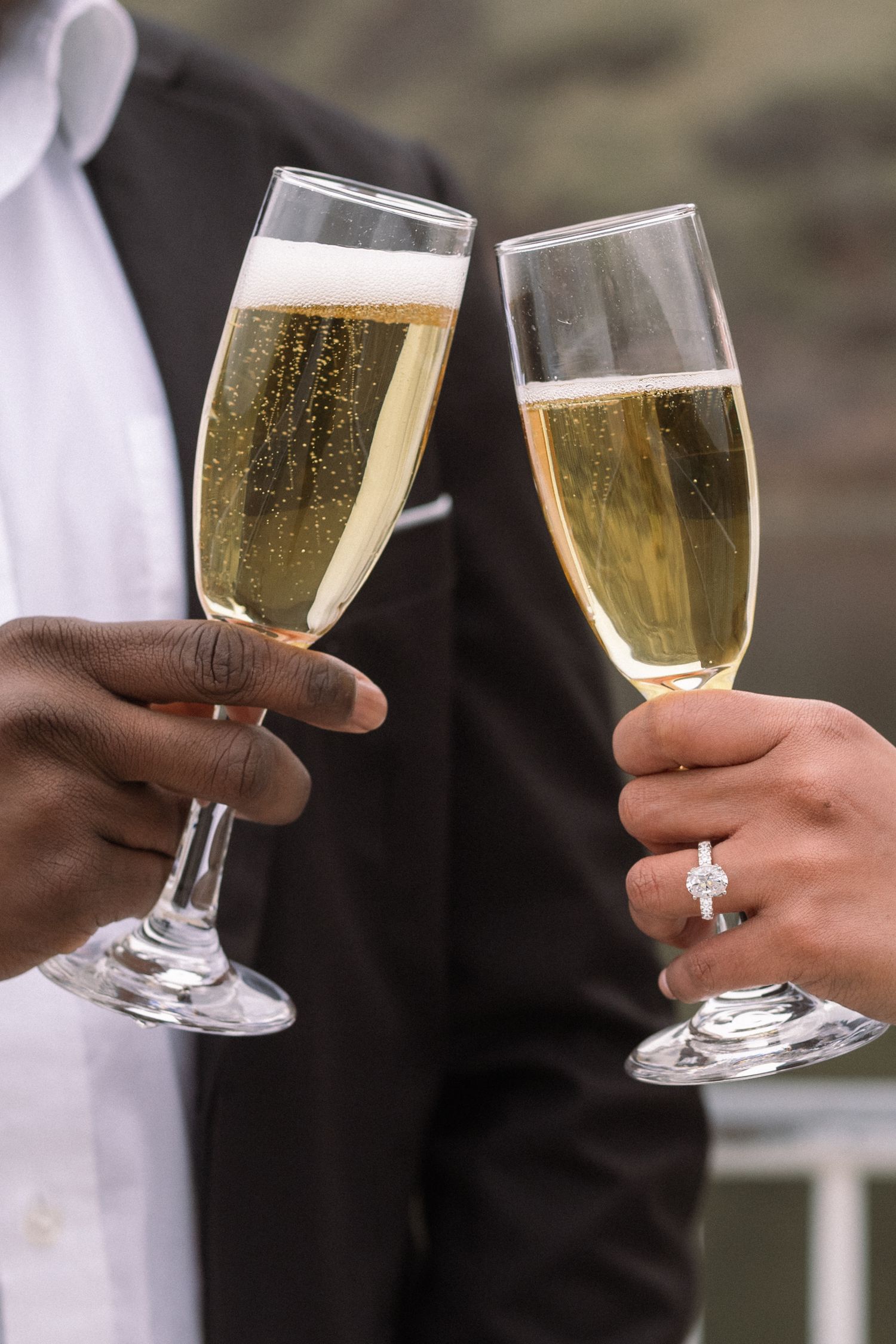 Two champagne flutes clink together in a celebratory toast against a natural backdrop.