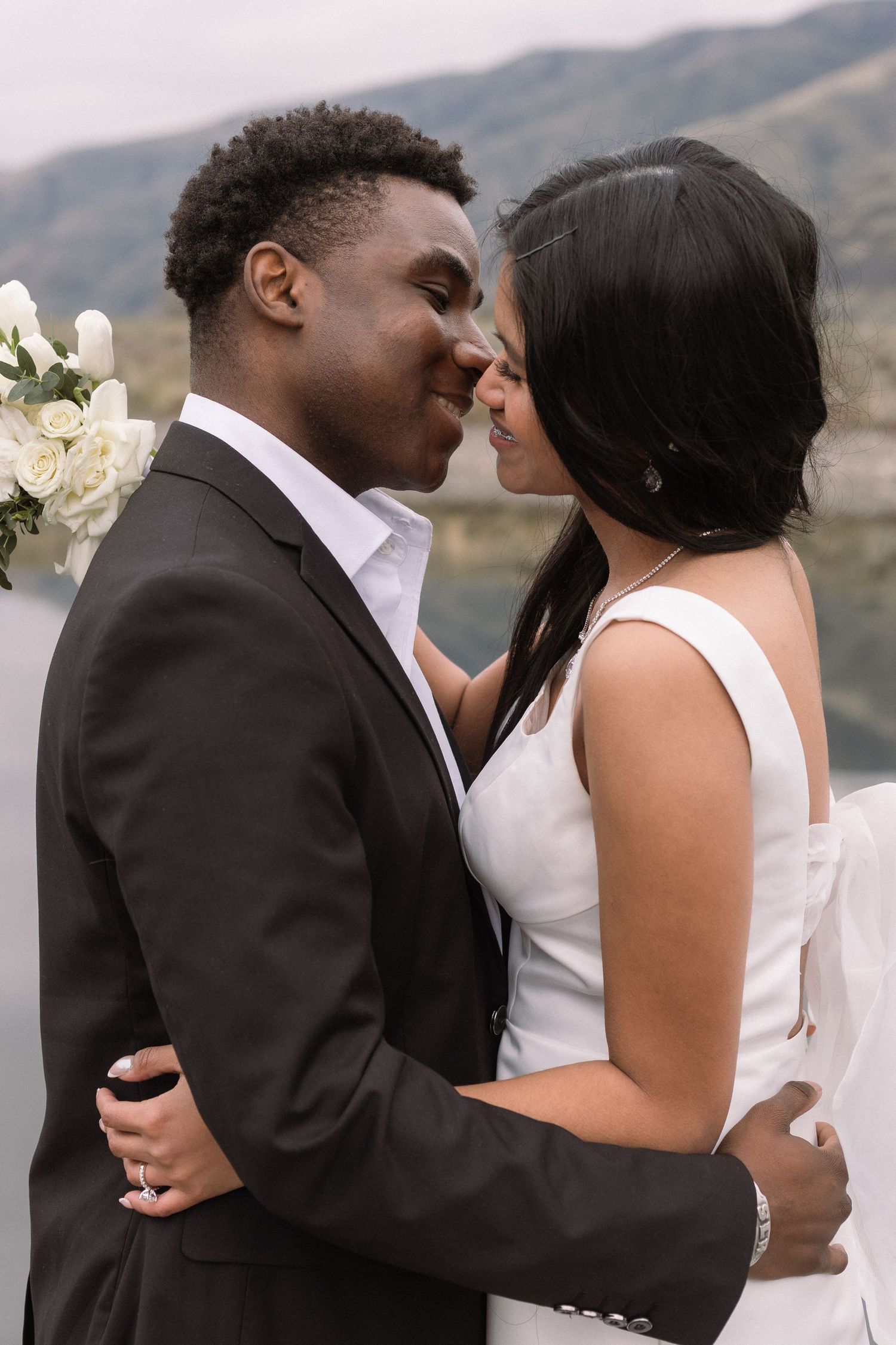 An intimate moment between newlyweds with mountains in the background.