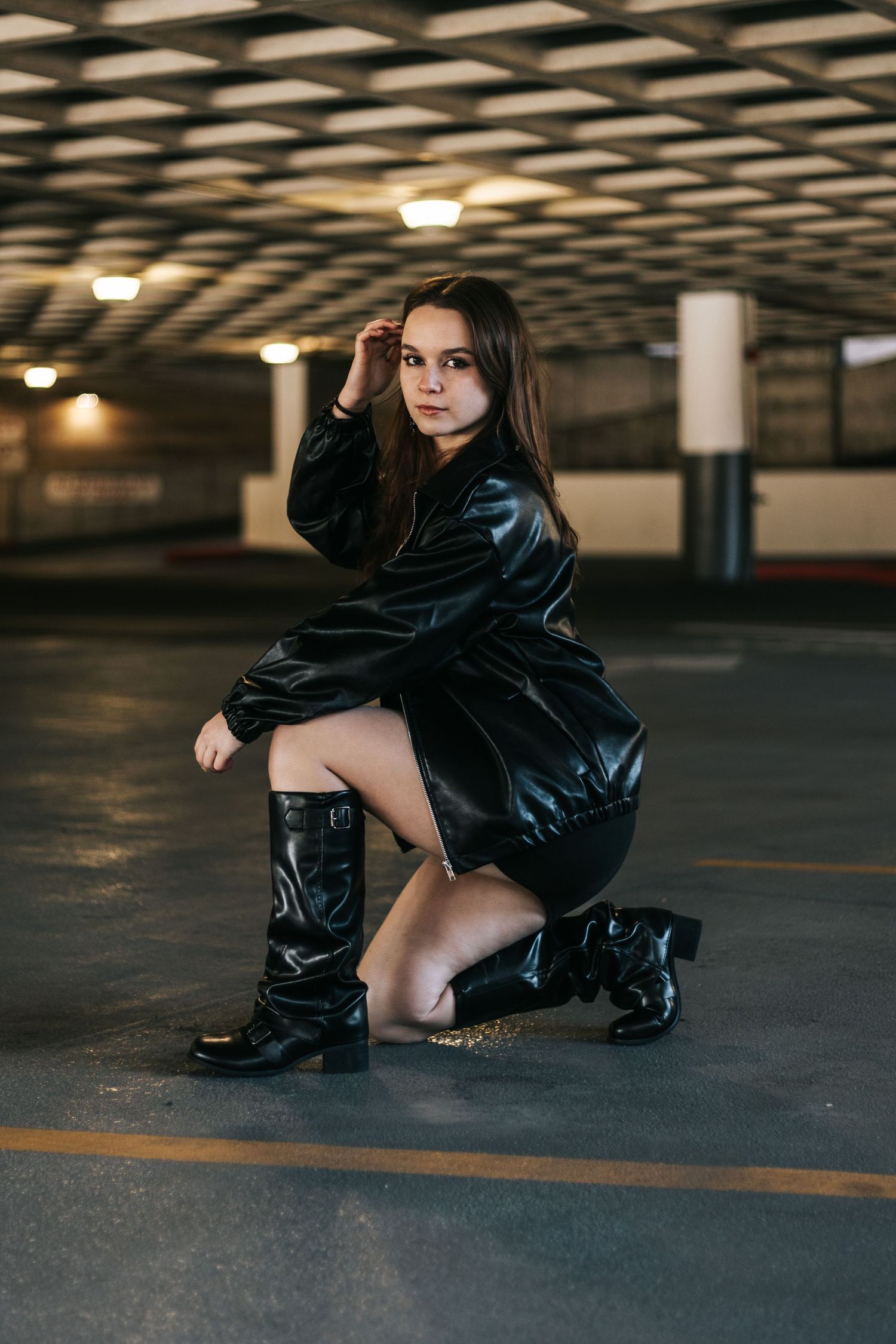 Artistic fashion photoshoot in dark parking garage featuring black leather outfit and dramatic poses.