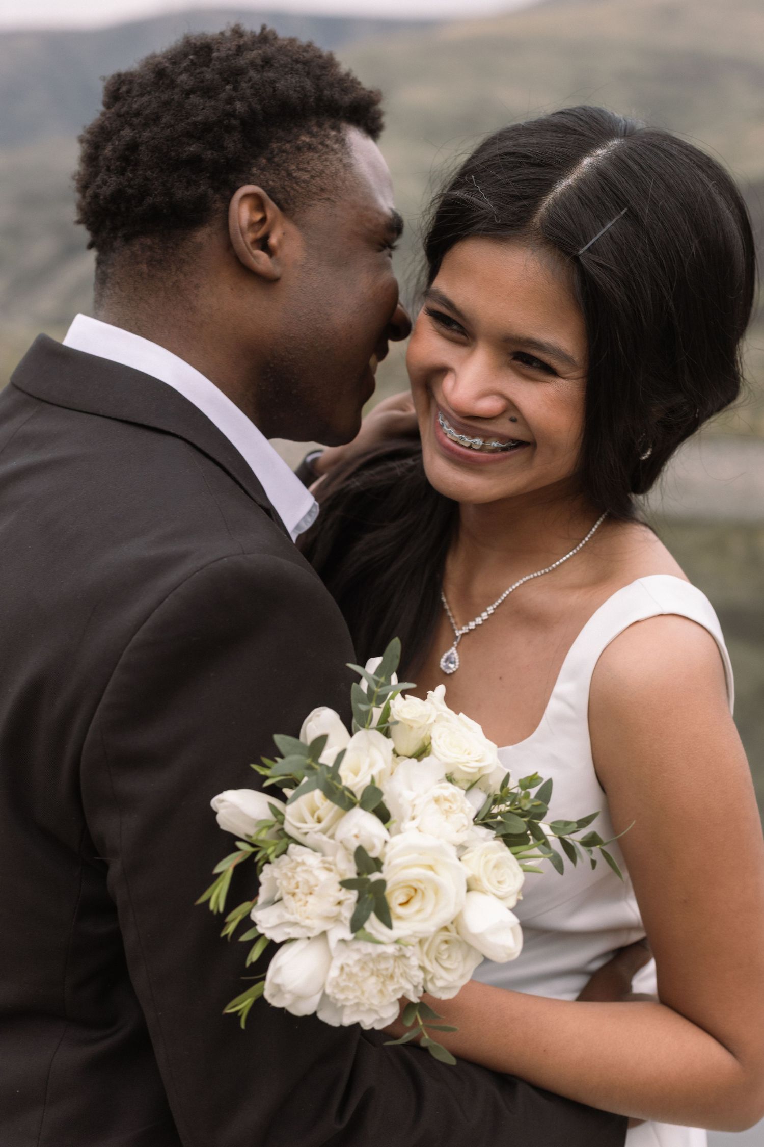 A couple sharing a joyful moment with white roses at their wedding.