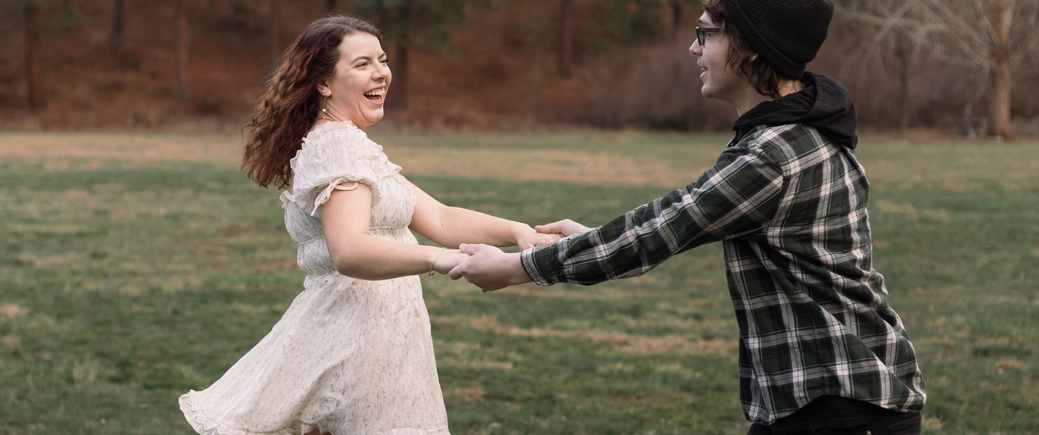 A playful outdoor photoshoot with a couple dancing and twirling in autumn scenery.