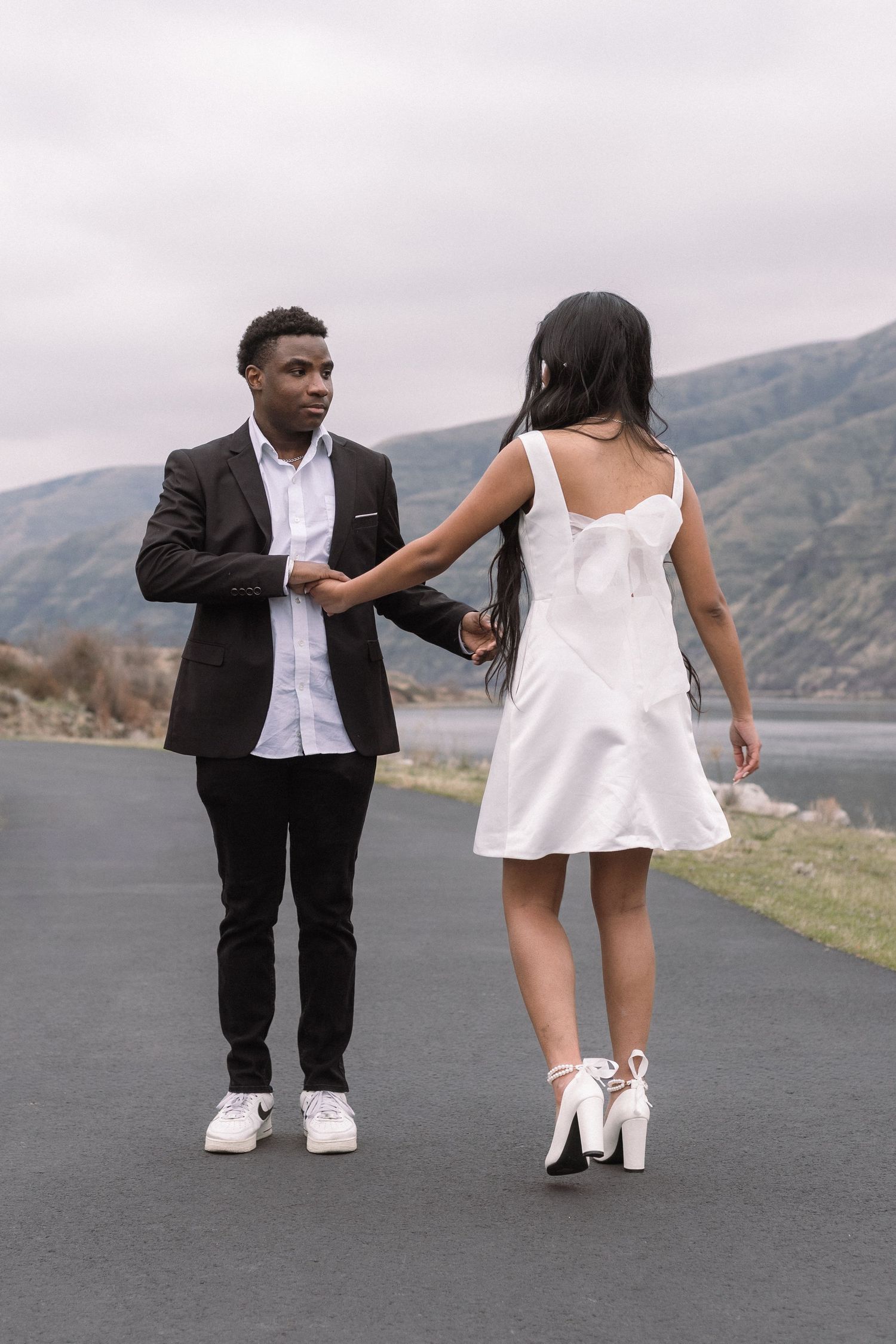 A playful moment between a couple on a lakeside road.