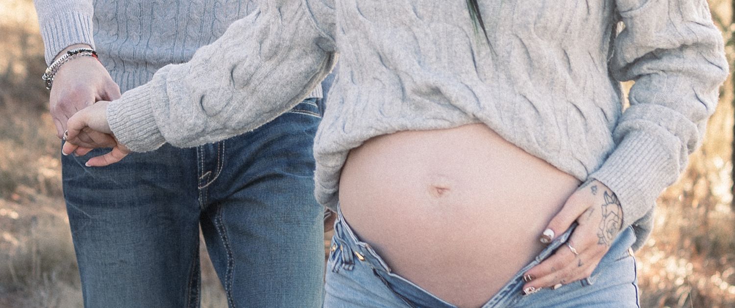 Close-up maternity photos highlighting pregnancy bump in natural outdoor setting.