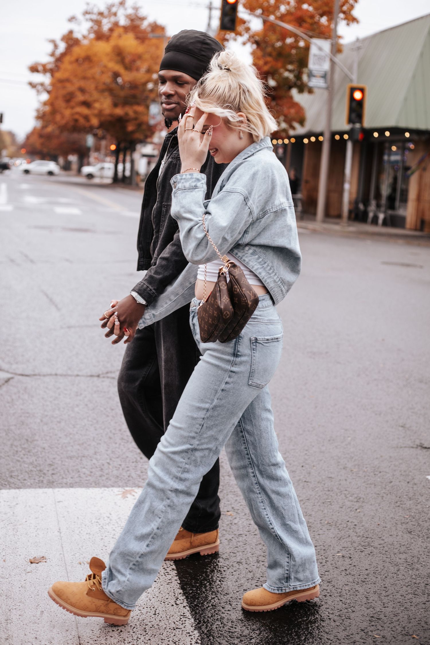 A couple playfully dancing together on a rainy autumn day wearing casual outfits and boots.