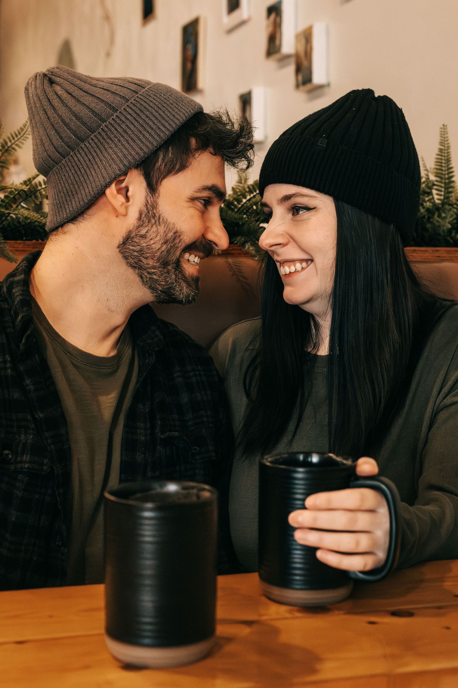 A couple shares an intimate moment while drinking coffee at a wooden table in warm lighting.