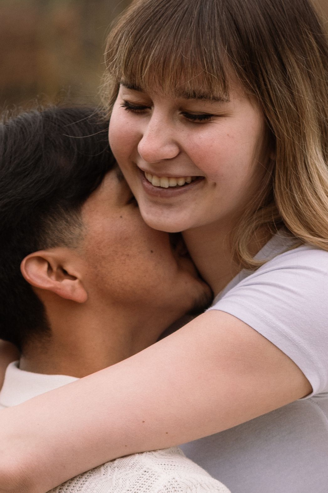 A couple shares an intimate embrace while smiling and showing affection in a series of close-up shots.