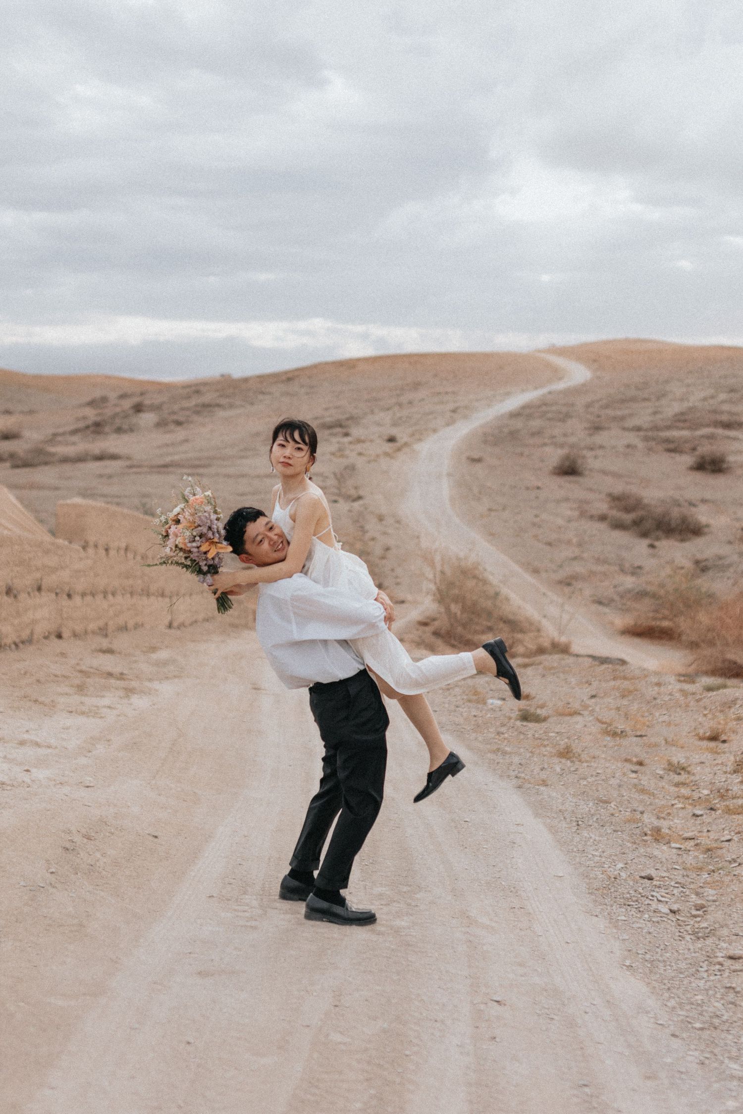 Groom lifting bride in the Agafay desert during golden hour