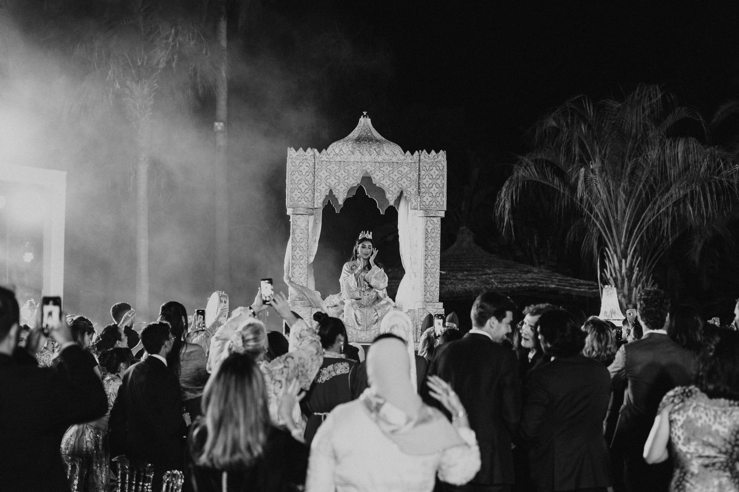 Bride seated in a traditional Moroccan Amaria carried by four men during the wedding procession
