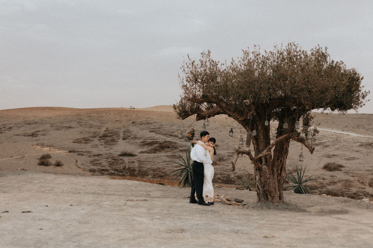Bride and groom posing in the Agafay desert at sunset