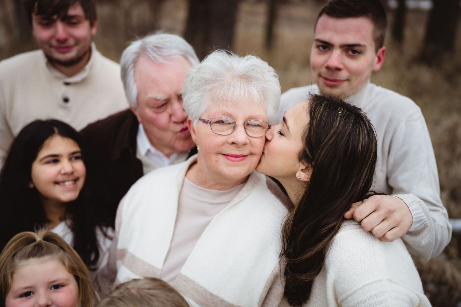 A multi-generational family gathering together for a warm portrait outdoors.