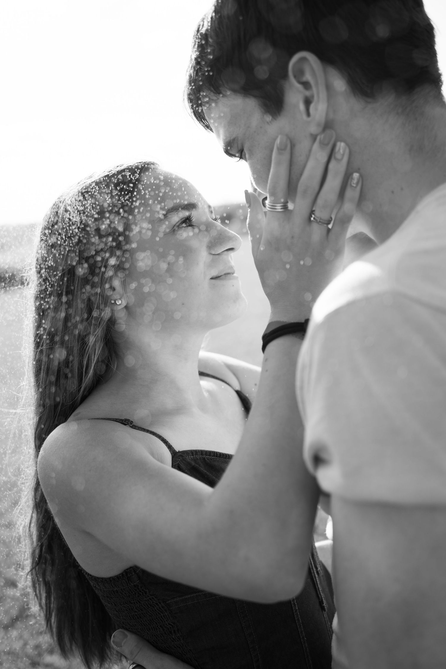 Black and white close-up captures intimate moment between couple outdoors.