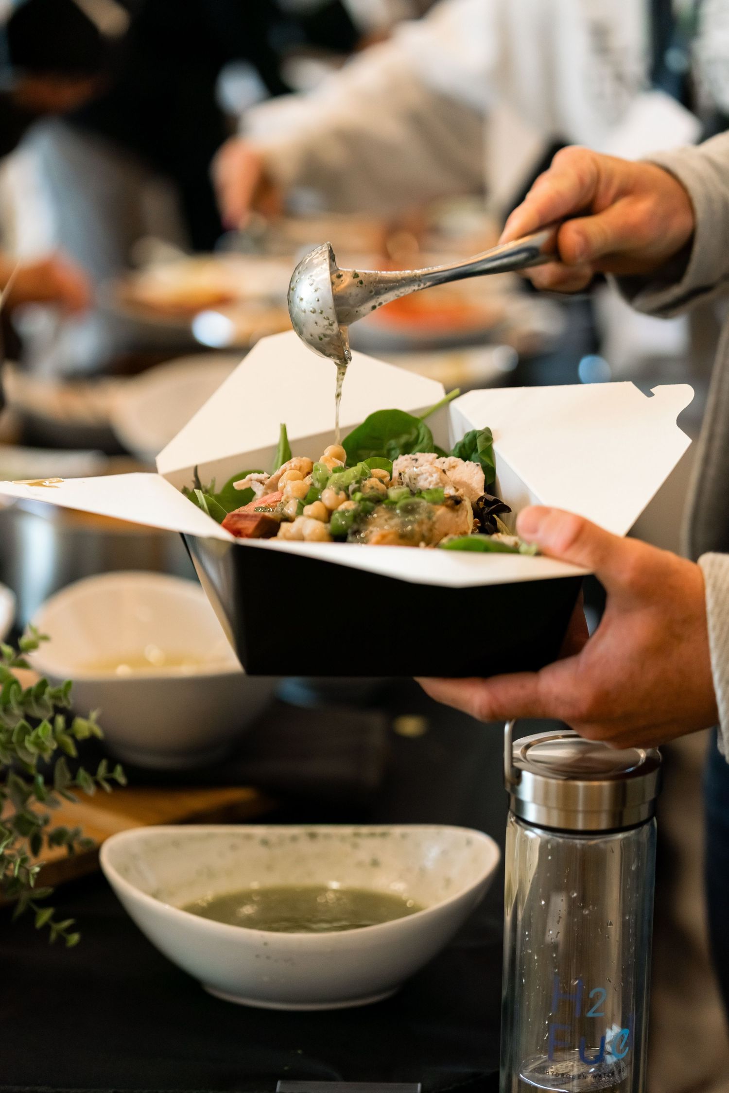 Hands serving elegant plated dishes at an upscale dining event.