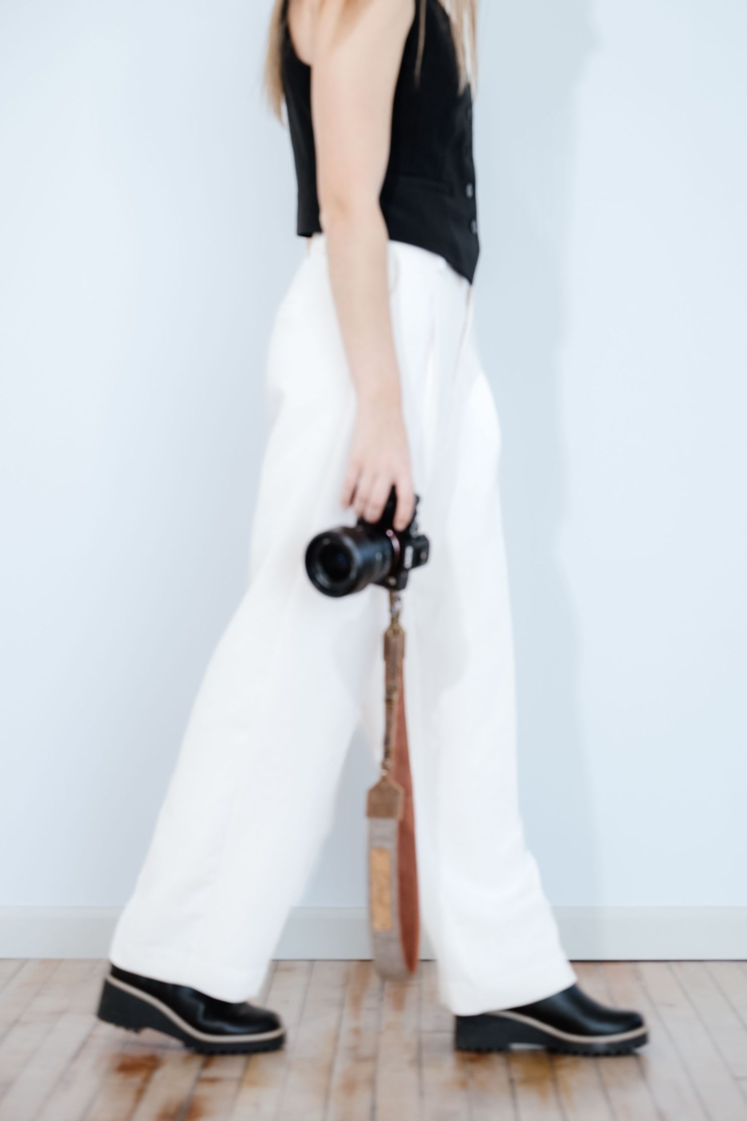 Close-up of black shoes and white pants walking against white background.