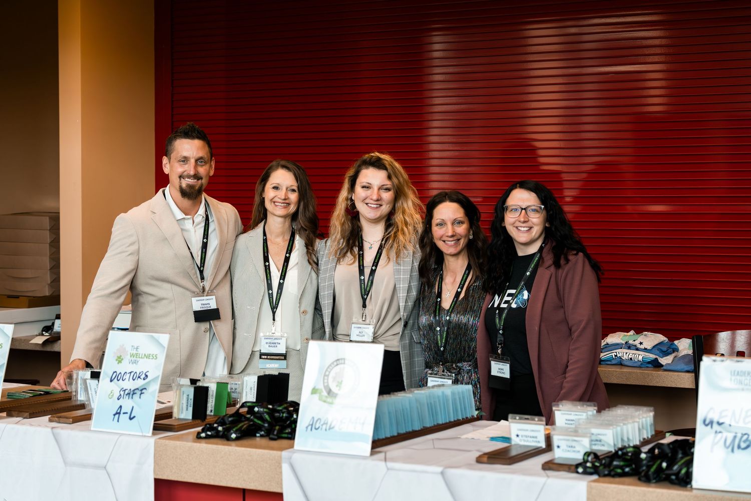 Trade show booth staff posing together behind product display table.