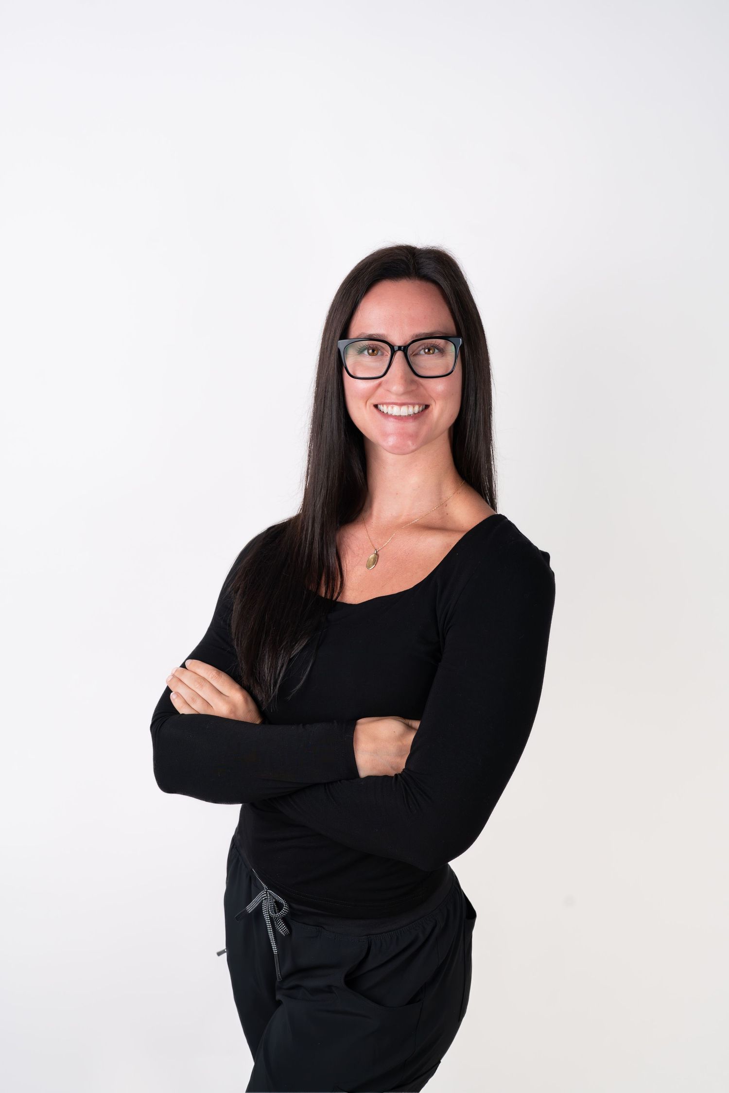 Professional in black attire and glasses poses confidently against white background.