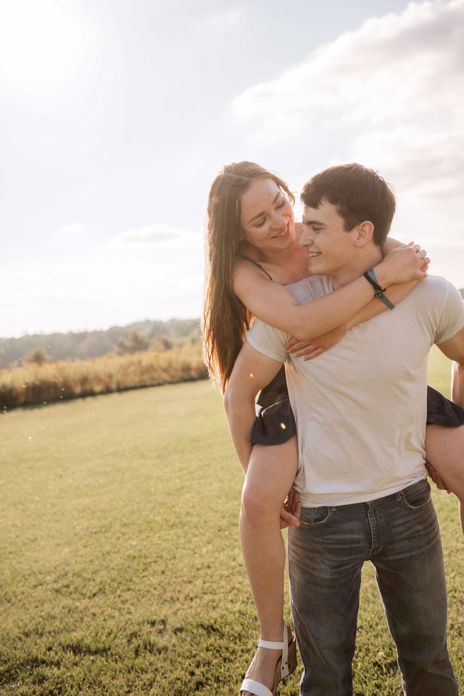 A couple shares an intimate moment while embracing in a sunny field.