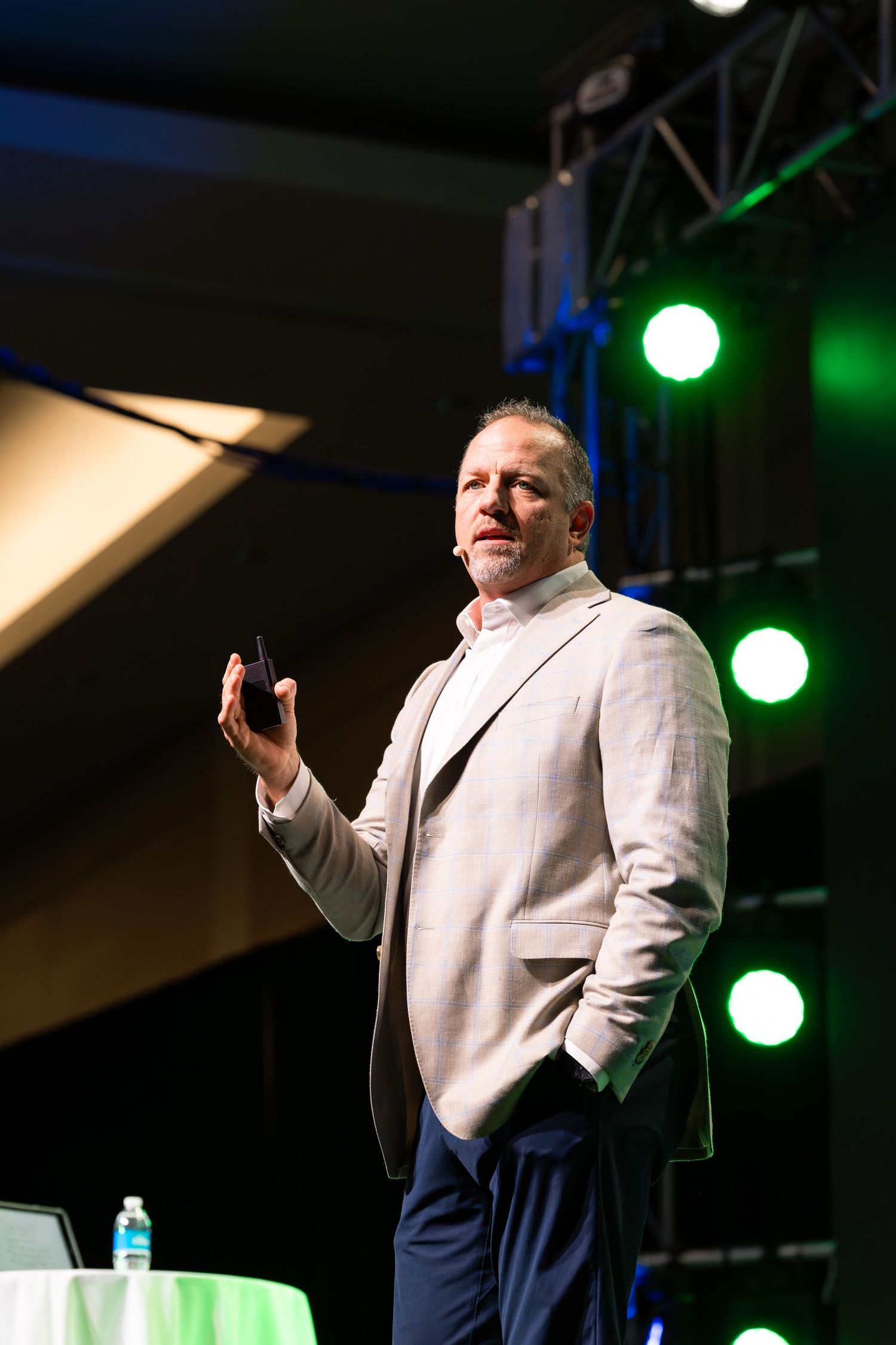 Speaker presenting on stage with dramatic lighting and professional event setup.