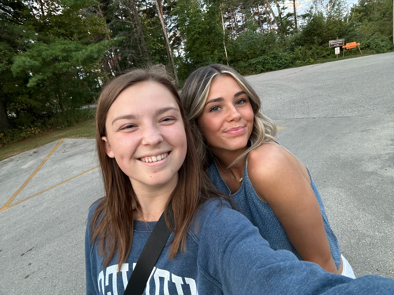Two friends take a casual outdoor selfie in matching blue shirts.
