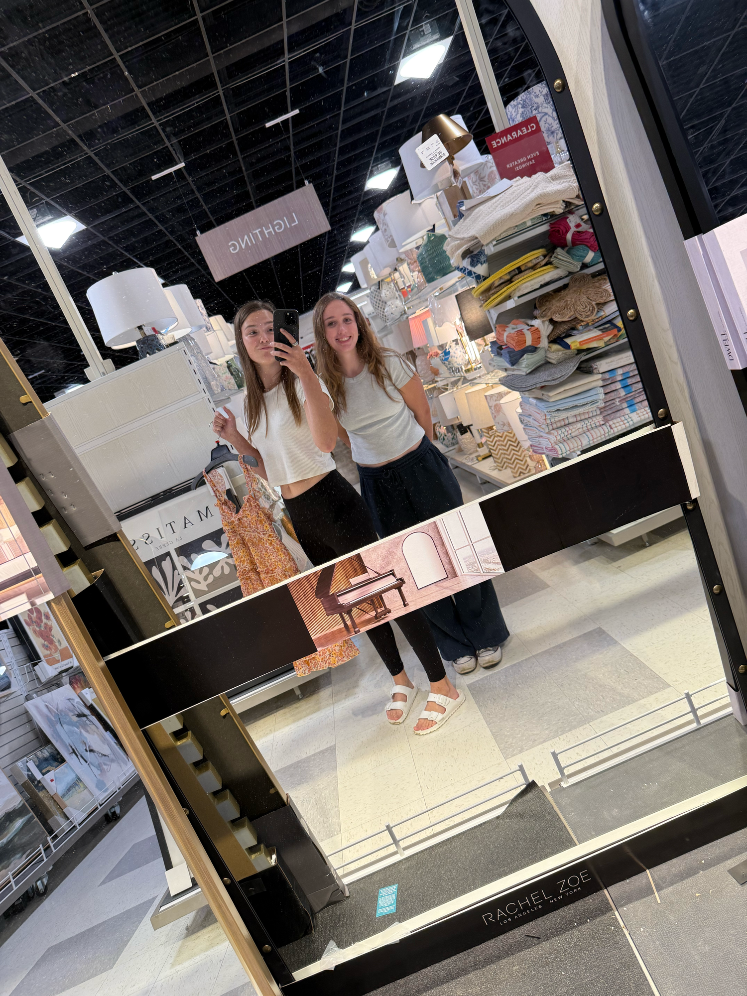 Two people take a mirror selfie while shopping in a retail store.