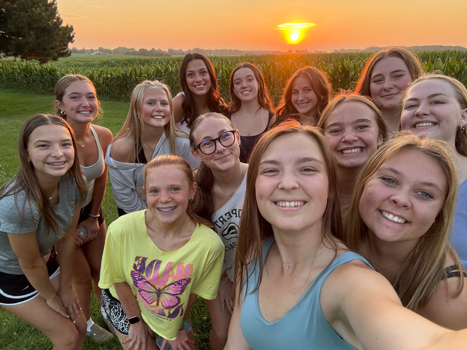 A group photo taken during golden hour sunset with a cornfield in the background.