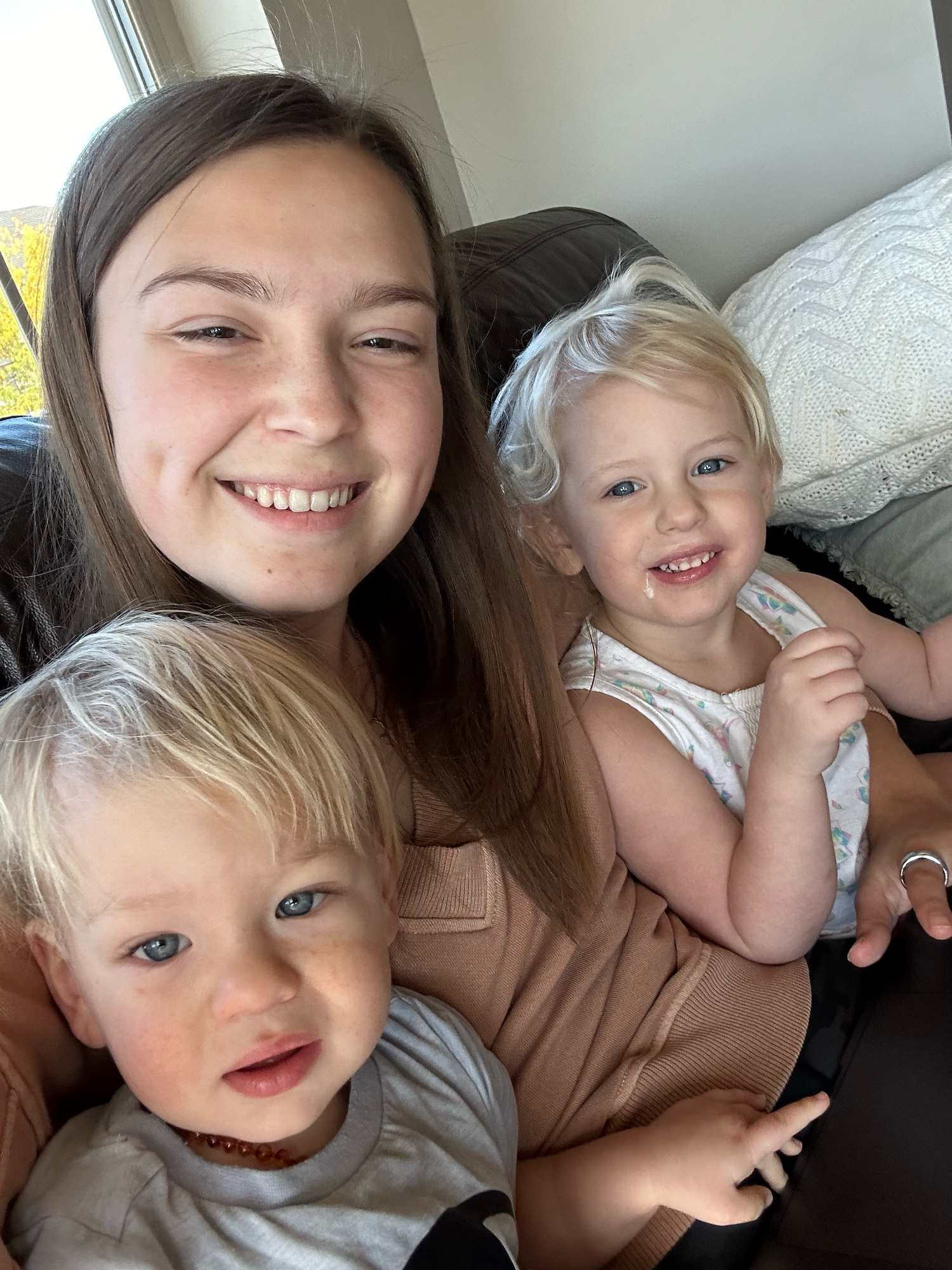 A heartwarming selfie with two small children with blonde hair on a couch.