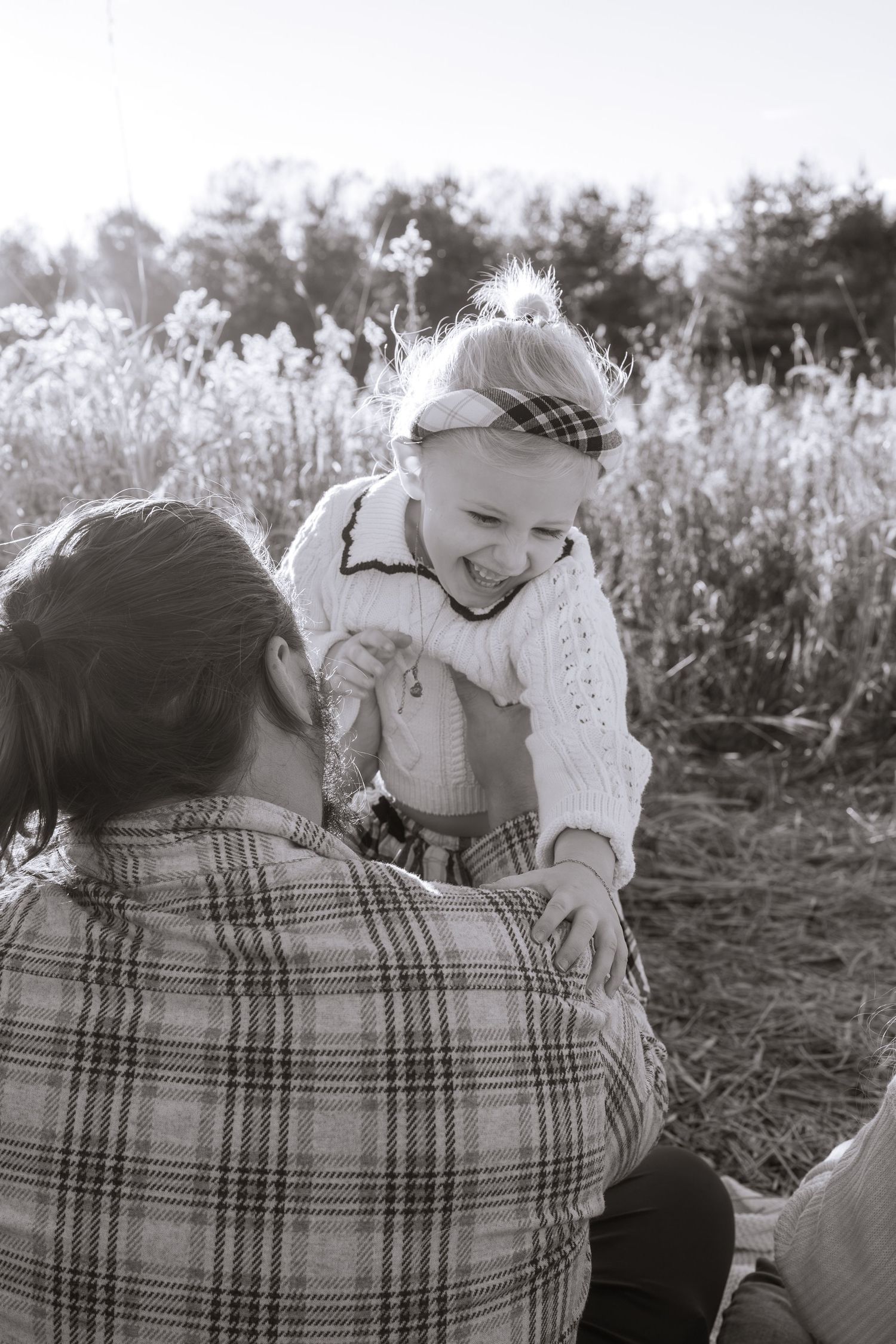 Family cuddles together on blanket in black and white photo.