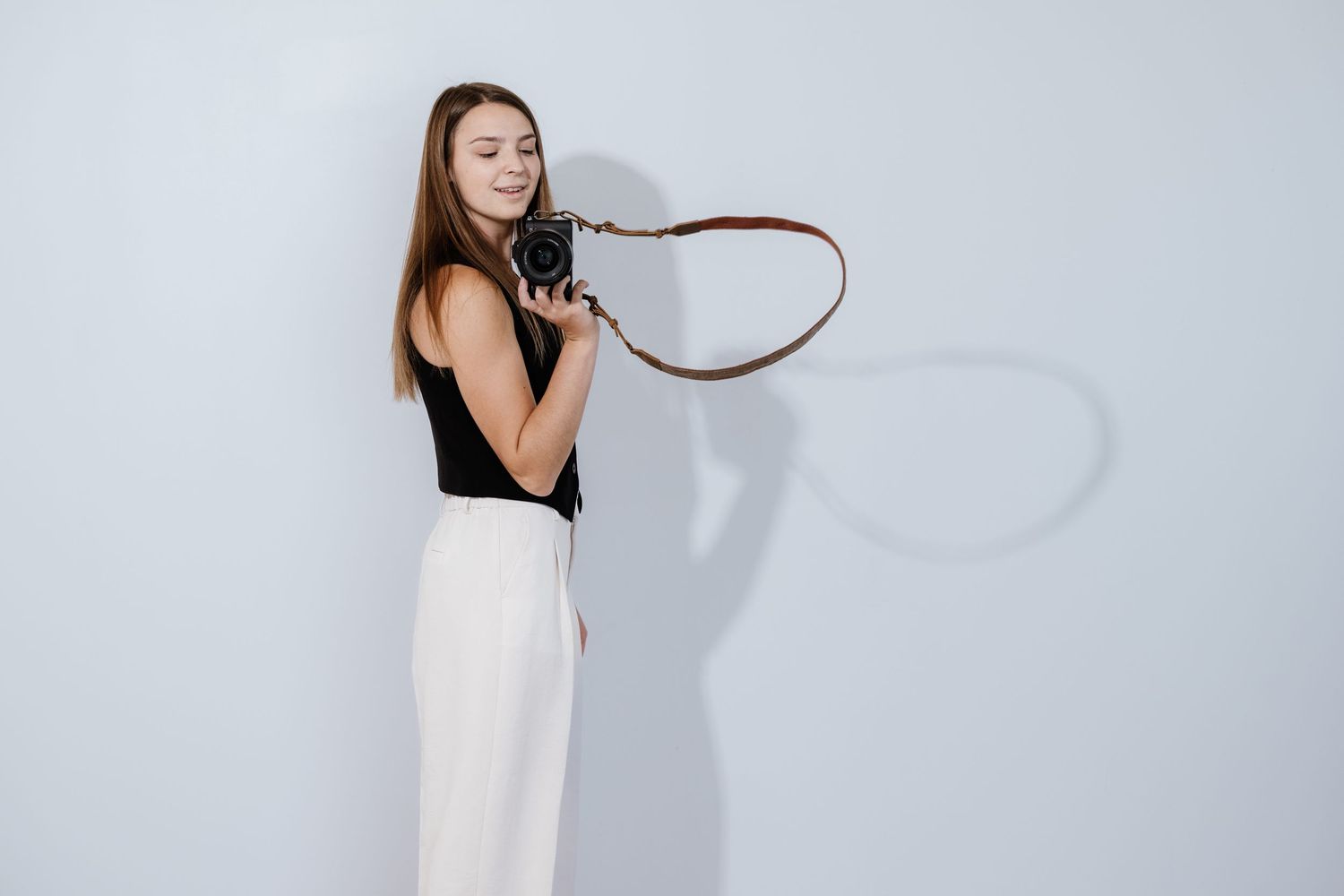 Artistic series of photographer poses with camera against white minimalist background.
