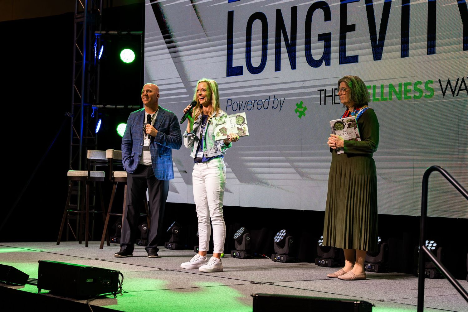 Stage presentation with 'Longevity' text displayed on large screen in background.