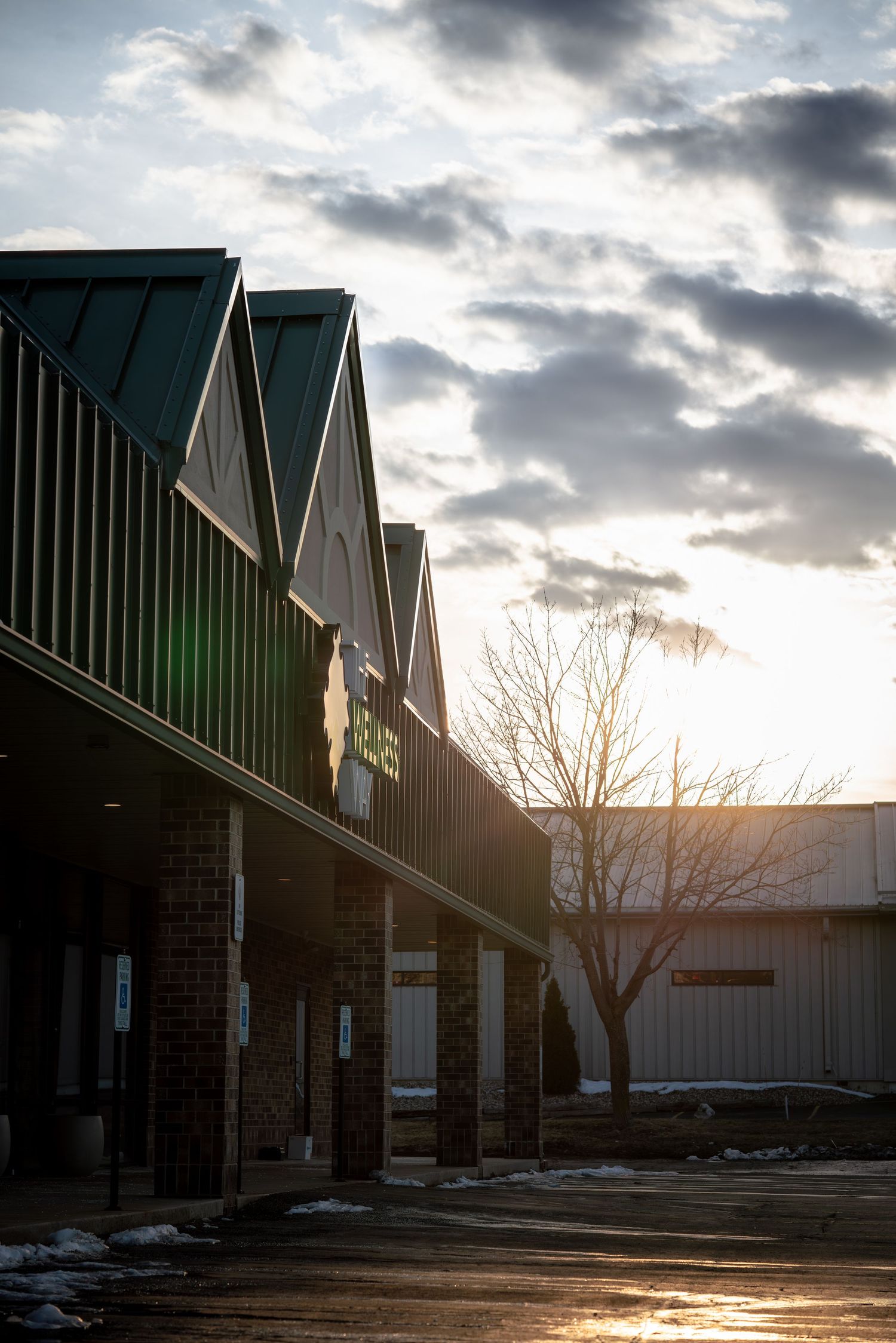 Modern commercial building exterior with angular roofline silhouetted against dramatic cloudy sunset sky.