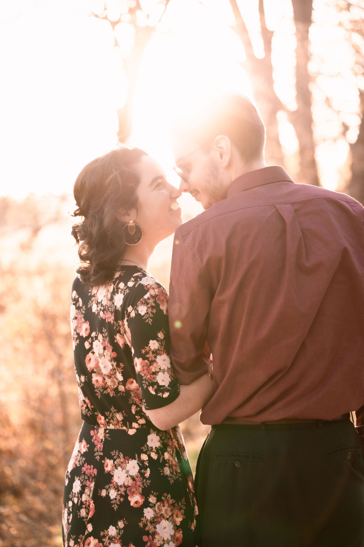 Couple sharing intimate moment in golden sunlight through trees.