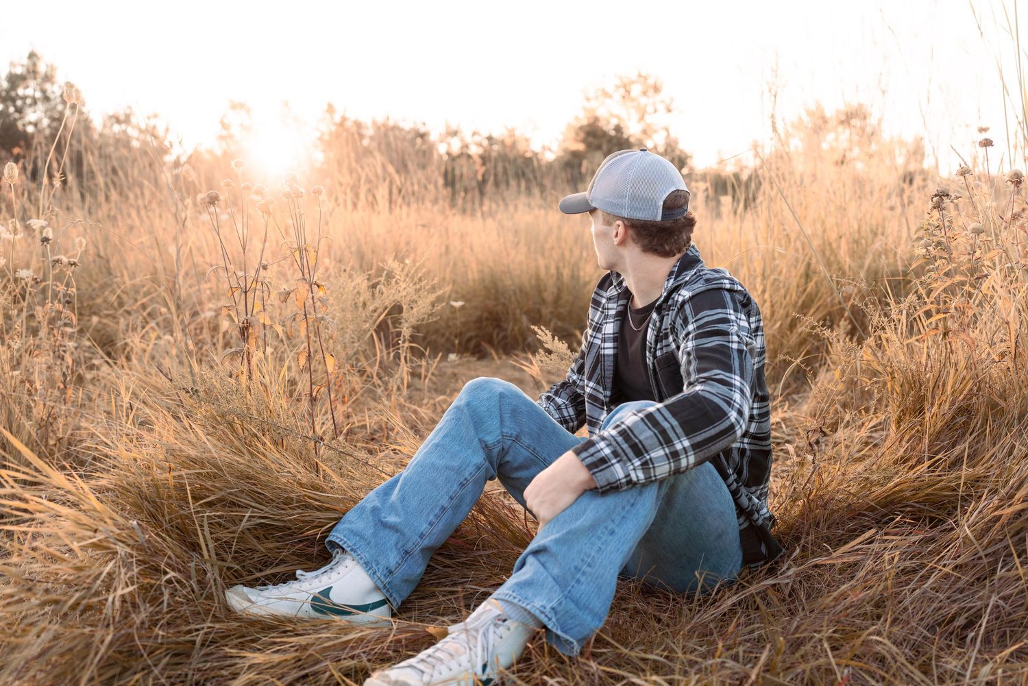 Person relaxing in tall grass during golden hour while taking photographs.