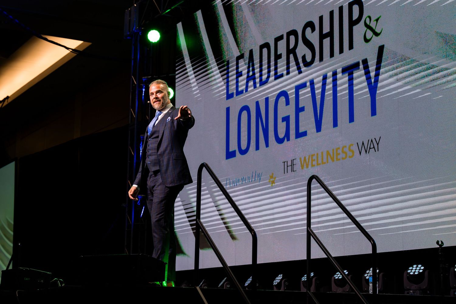 Conference stage with 'Leadership & Longevity' text displayed on large screen.