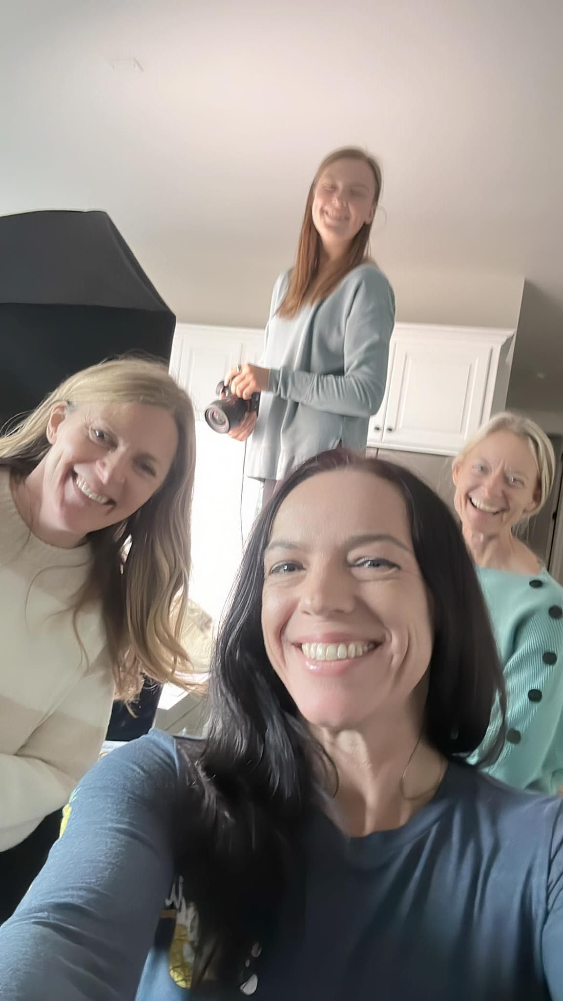 Friends taking cheerful selfies together in a bright indoor setting.