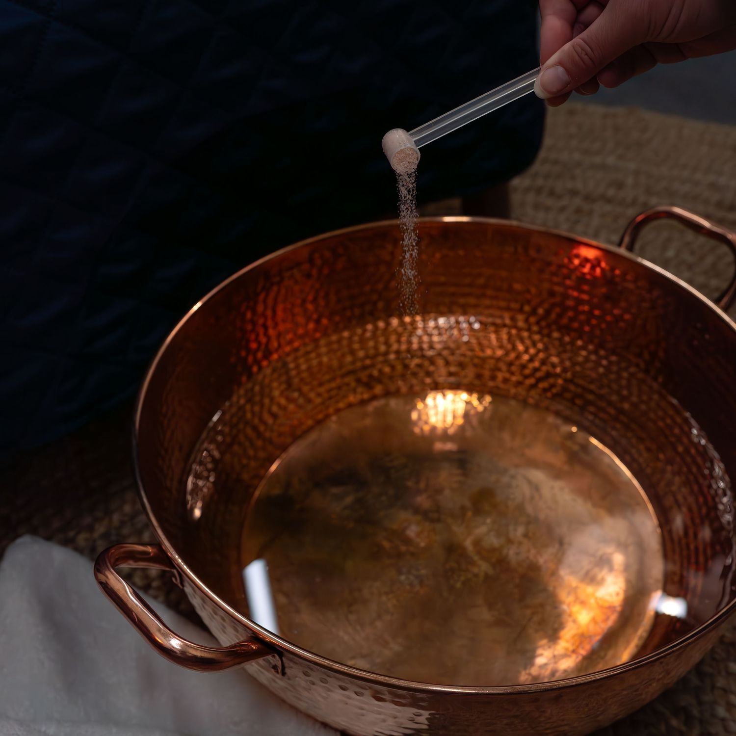 Copper pan being cleaned and polished in sequential steps.