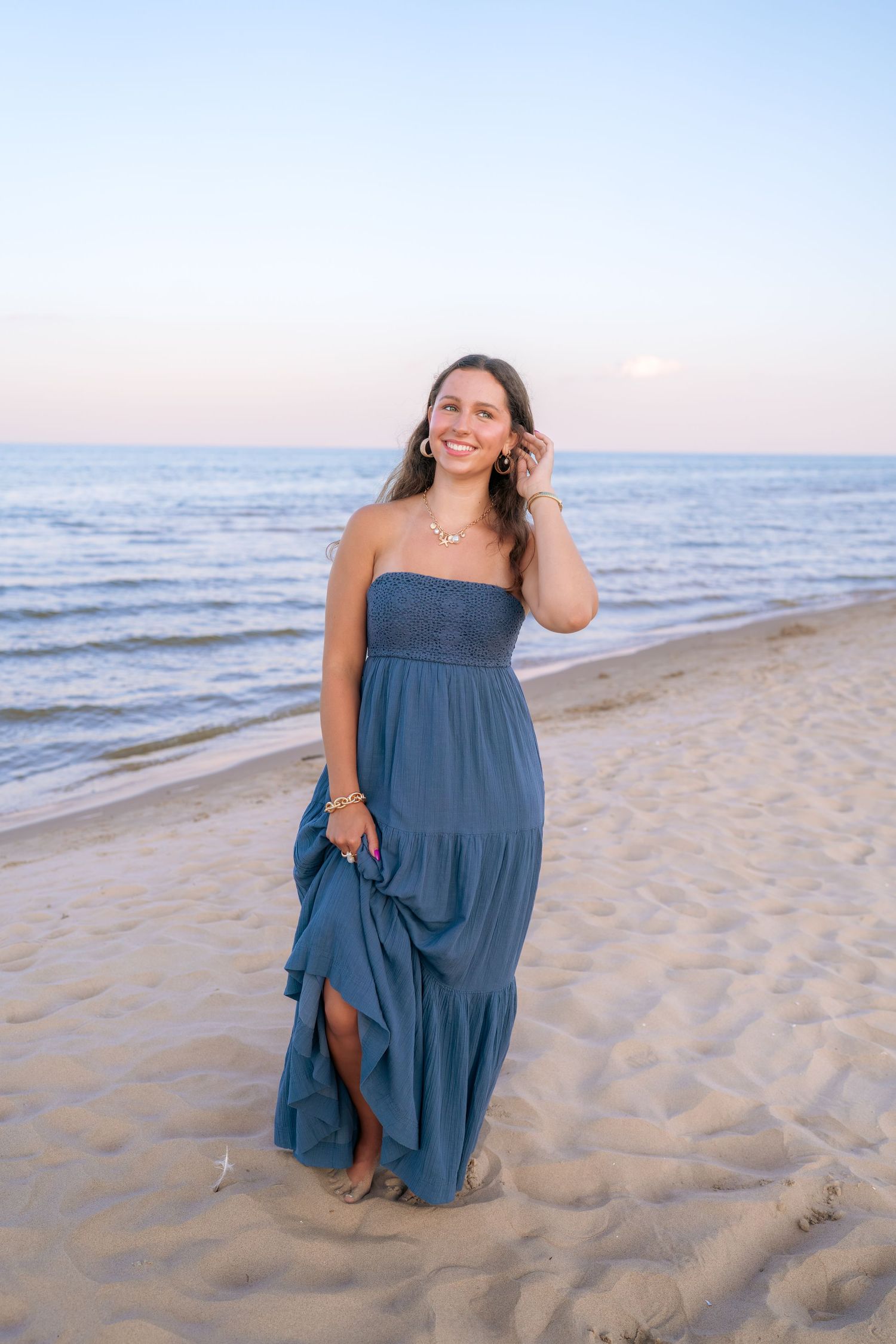 A beachside portrait captures someone in a navy tiered maxi dress at sunset.