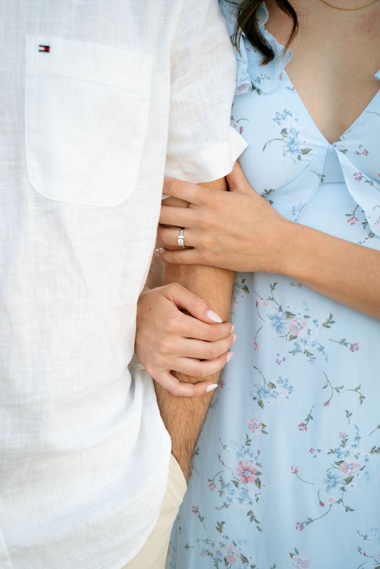 Close-up of hands embracing against a delicate floral blue background.