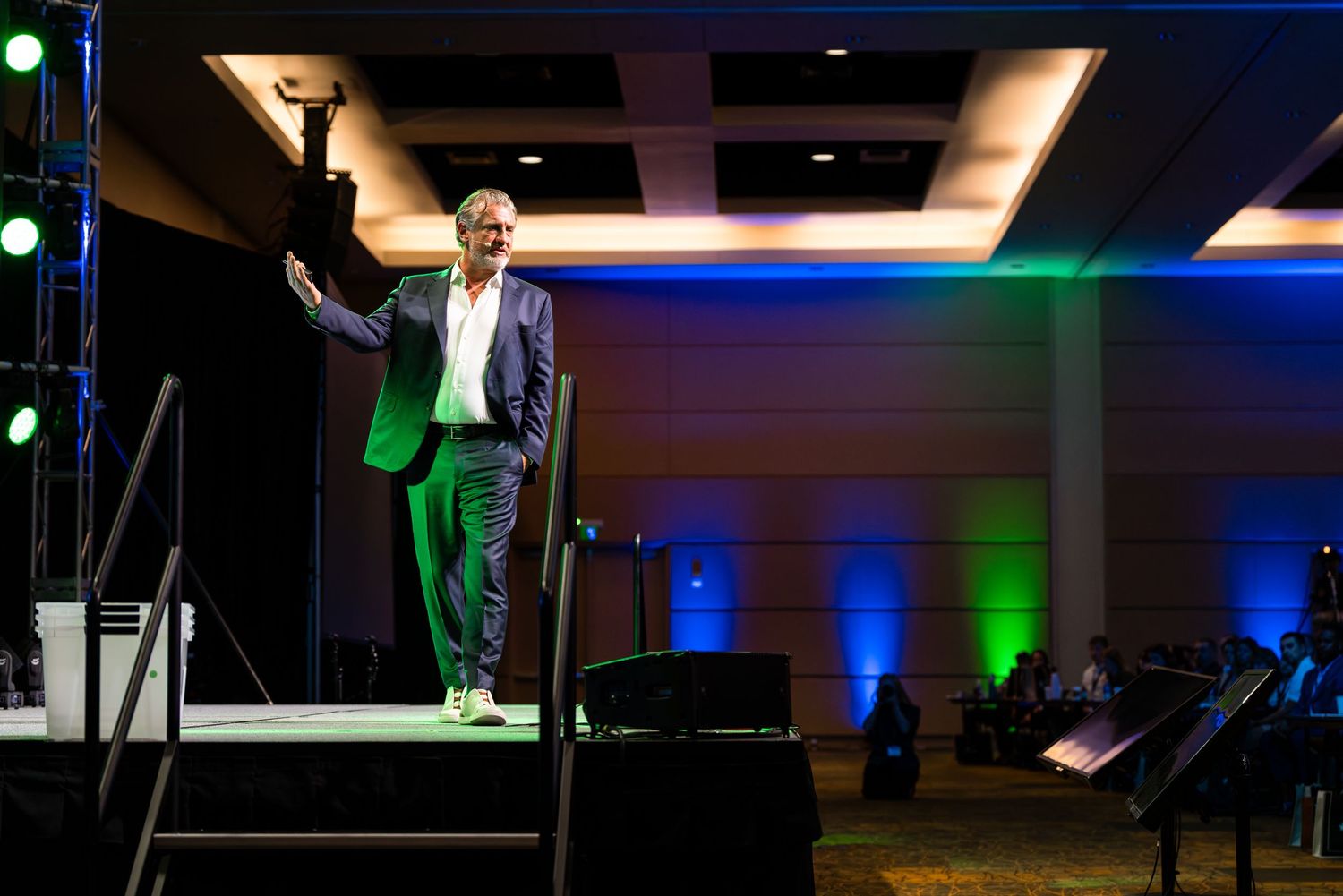 Wide shot of conference stage with dramatic blue and green lighting effects.