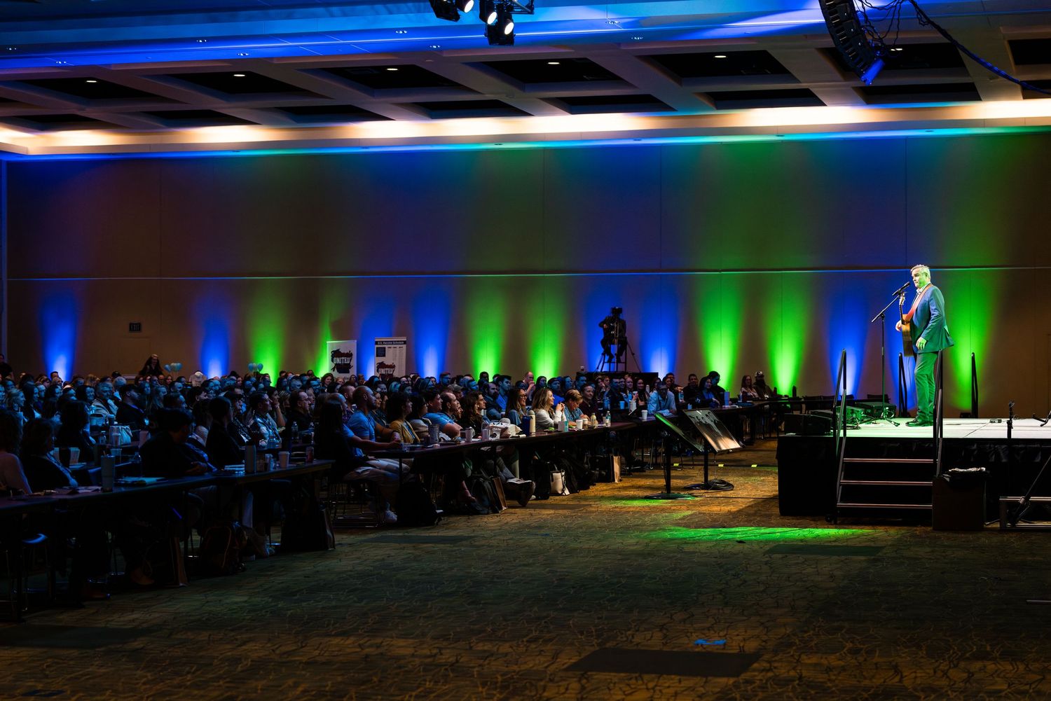 Stage setup with dramatic blue and green lighting for a conference event.