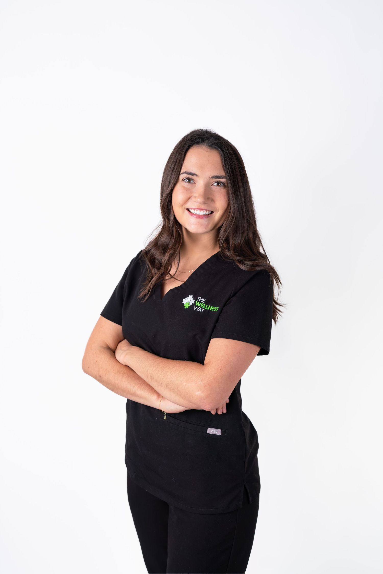 Medical professional in black scrubs smiles while posing against white backdrop.