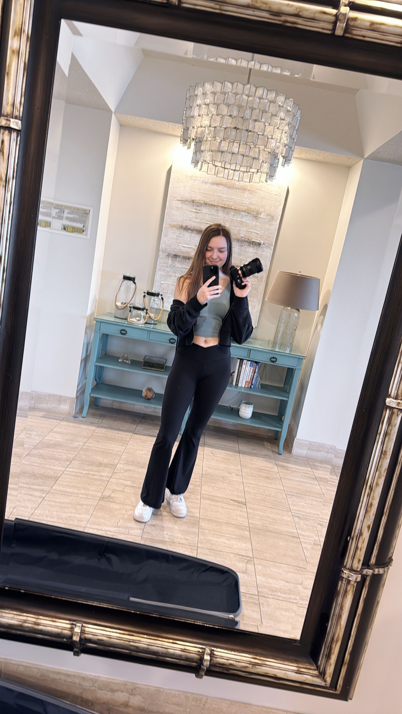 Mirror selfie in an elegant room with crystal chandeliers and tiled floors.