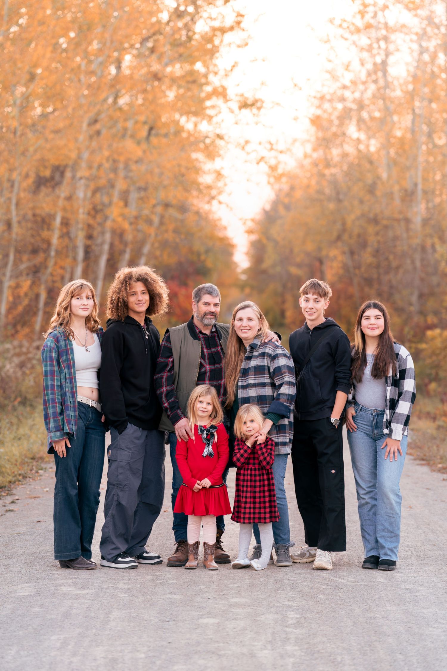 Large family group photo on path surrounded by golden autumn trees.